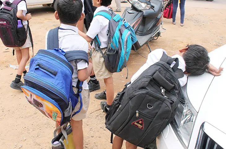 niños cargando mochilas pesadas del colegio